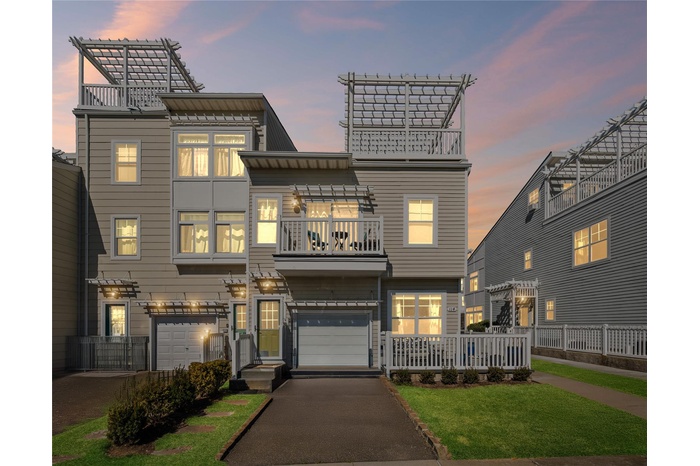 View of front facade featuring a balcony, a lawn, a garage, and aphalt driveway