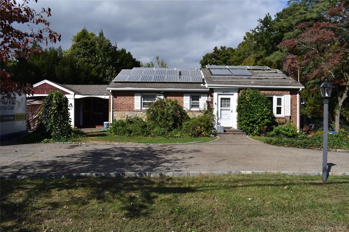 Ranch-style home featuring roof mounted solar panels, brick siding, a front yard, and a chimney
