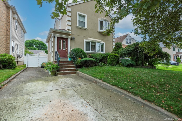 Traditional-style home featuring stucco siding, a front yard, and a gate