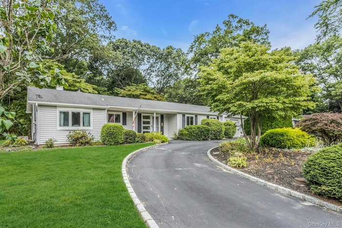 Ranch-style home with a front yard, asphalt driveway, and roof with shingles