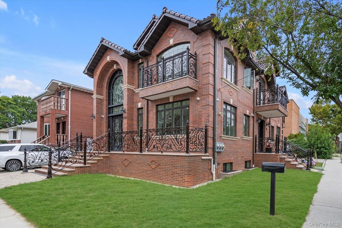 View of front of house featuring a front lawn, brick siding, and a balcony