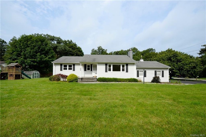 Ranch-style house featuring a playground, a shed, a chimney, and a front lawn