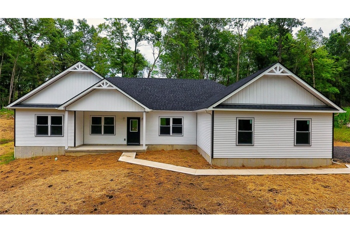 View of front of house featuring a shingled roof and view of wooded area