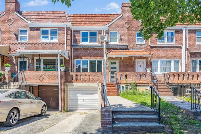 View of property with a garage, brick siding, and driveway