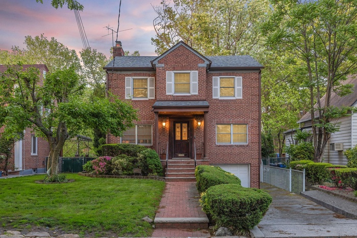 View of front of home with brick siding, a chimney, a garage, and a shingled roof
