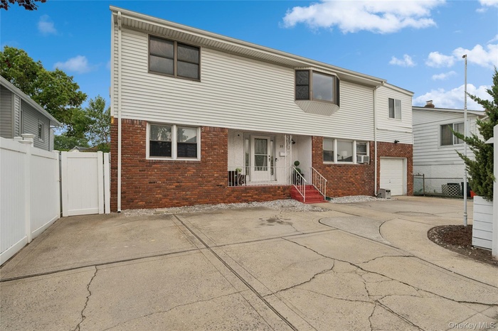 View of front of home with brick siding, concrete driveway, and a garage