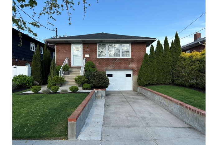 View of front of property featuring a garage, a front yard, brick siding, and driveway