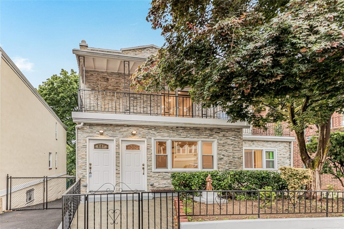 View of front of home featuring a balcony, a fenced front yard, a gate, and stone siding