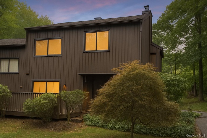 View of front of house featuring a chimney, a wooden deck, and a shingled roof