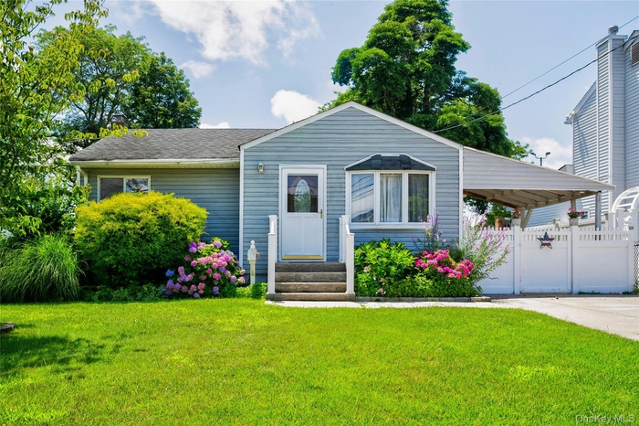 View of front of house with entry steps, concrete driveway, and a gate