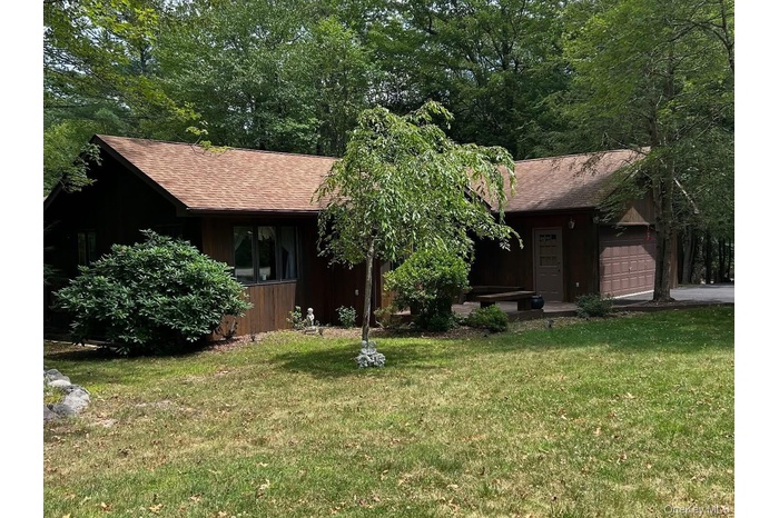 View of front facade featuring roof with shingles, an attached garage, and a front lawn