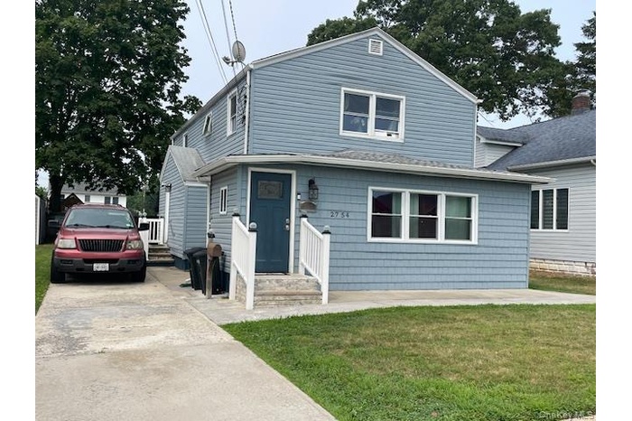 View of front of home with a front lawn, driveway, and a shingled roof