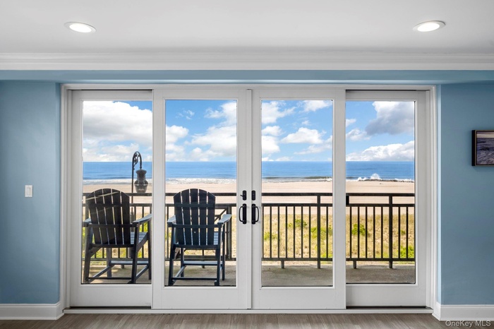 Doorway to outside featuring view of water and beach, wood finished floors, plenty of natural light, crown molding, and recessed lighting