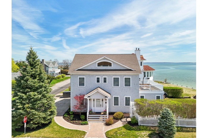 Greek revival inspired property featuring fence, a water view, a balcony, and a chimney