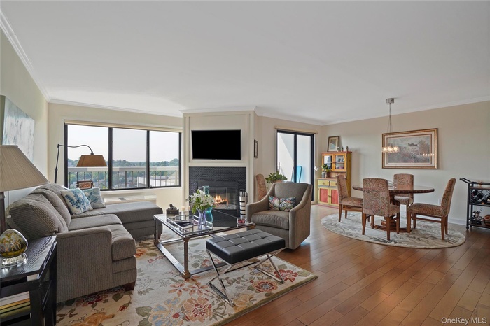 Living area featuring healthy amount of natural light, crown molding, a fireplace, and wood finished floors