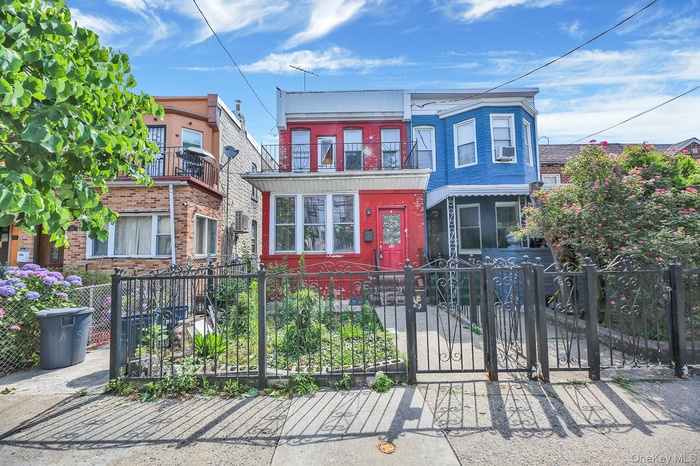 Traditional-style house featuring a fenced front yard, a balcony, brick siding, and a gate