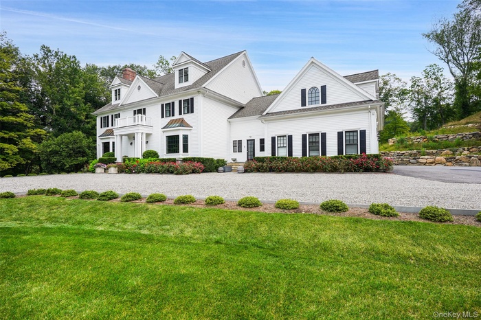 View of front of home with a balcony, a front lawn, and roof with shingles