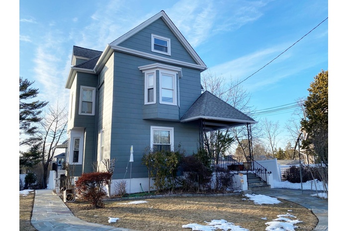 View of front of house featuring a shingled roof and covered porch