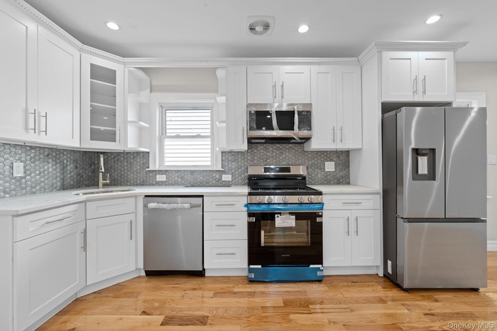 Kitchen with stainless steel appliances, white cabinetry, light countertops, and recessed lighting