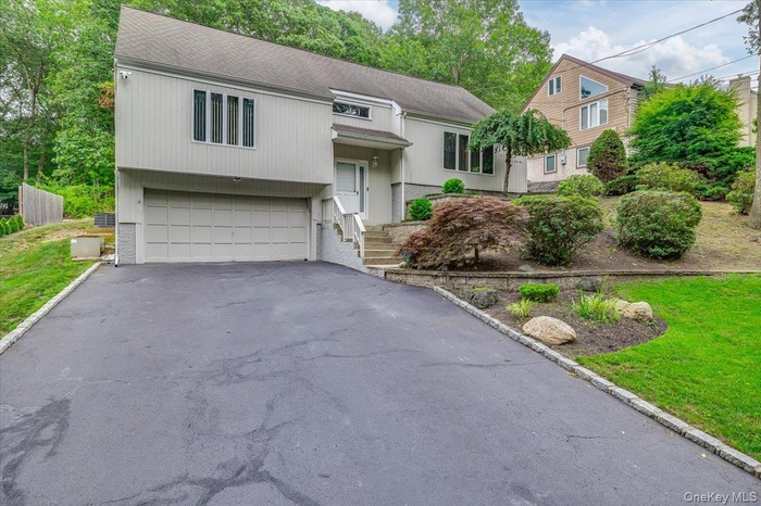 View of front of property featuring a garage, asphalt driveway, and a front lawn