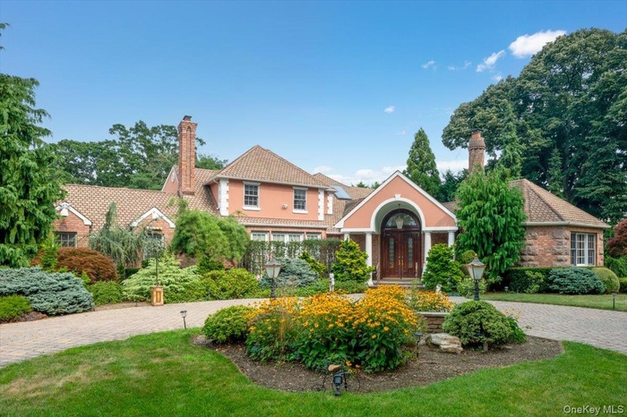 View of front facade with a chimney, decorative driveway, and a front lawn