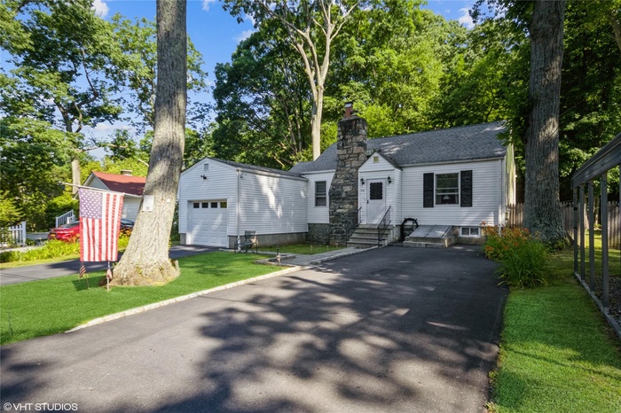 View of front of house with a chimney, aphalt driveway, a front yard, fence, and a shingled roof
