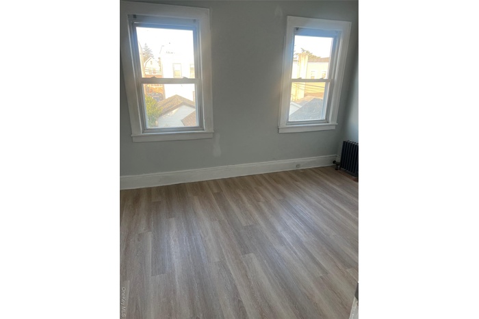 Unfurnished room featuring wood finished floors and radiator heating unit