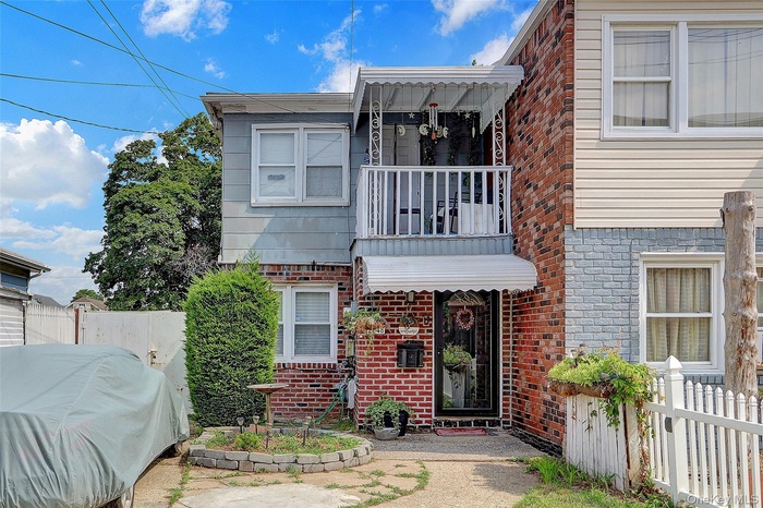 View of front of property with brick siding and a balcony