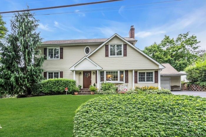 View of front of house with a chimney, a front lawn, and driveway