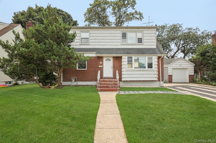View of front of property featuring roof with shingles, driveway, entry steps, and a front yard