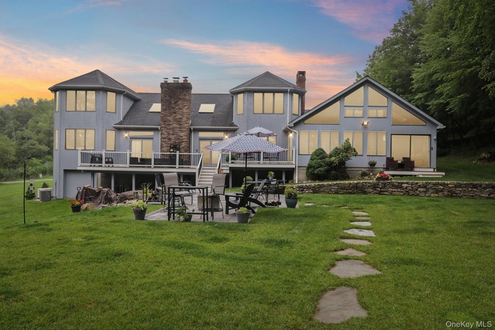 Back of house featuring a chimney, a patio area, a deck, and a yard