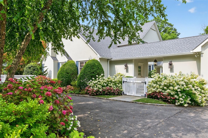 View of front of house featuring a gate, stucco siding, and roof with shingles