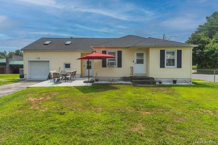 Back of house with a garage, a patio area, and driveway