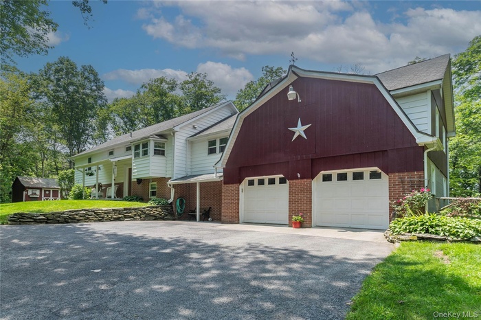 Dutch colonial featuring an outbuilding, a gambrel roof, asphalt driveway, and brick siding