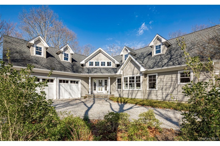 View of front of property featuring driveway, a shingled roof, and an attached garage
