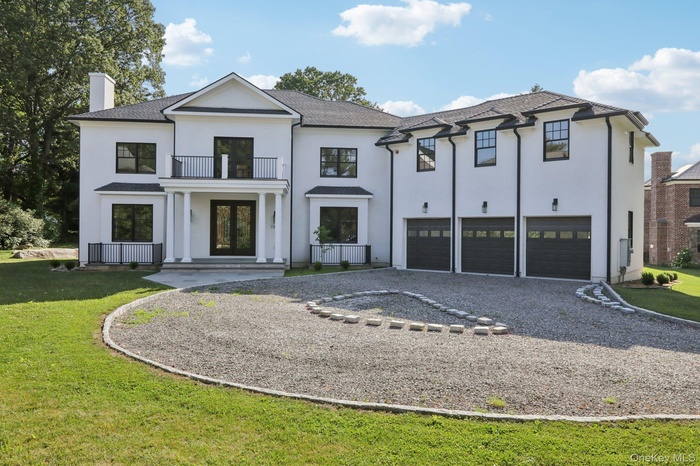 View of front facade featuring a balcony, driveway, a chimney, stucco siding, and a front yard