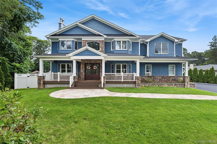 Craftsman-style house featuring a porch, a chimney, stone siding, a front yard, and a gate