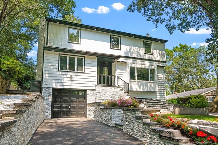 View of front facade featuring an attached garage, driveway, and stone siding