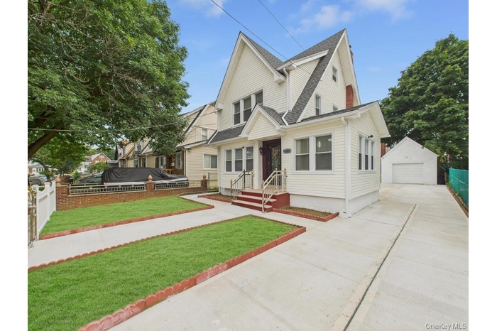 View of front facade with a garage, concrete driveway, an outdoor structure, and a shingled roof