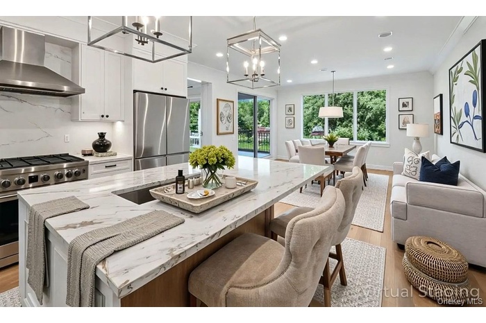 Kitchen featuring wall chimney range hood, appliances with stainless steel finishes, plenty of natural light, light wood finished floors, and recessed