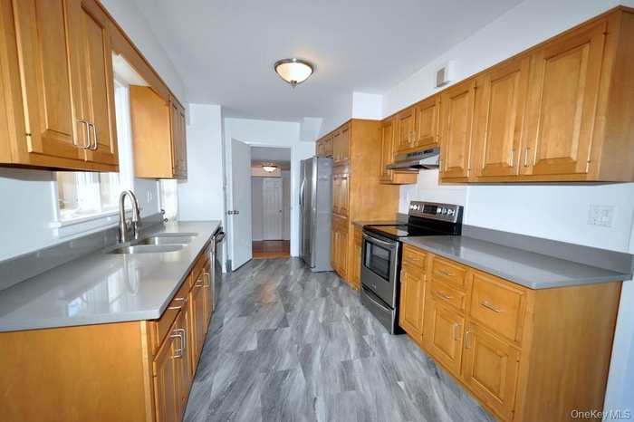 Large eat-in-kitchen with stainless steel appliances including a dishwasher, range and refrigerator, custom cabinets include roll out shelving.