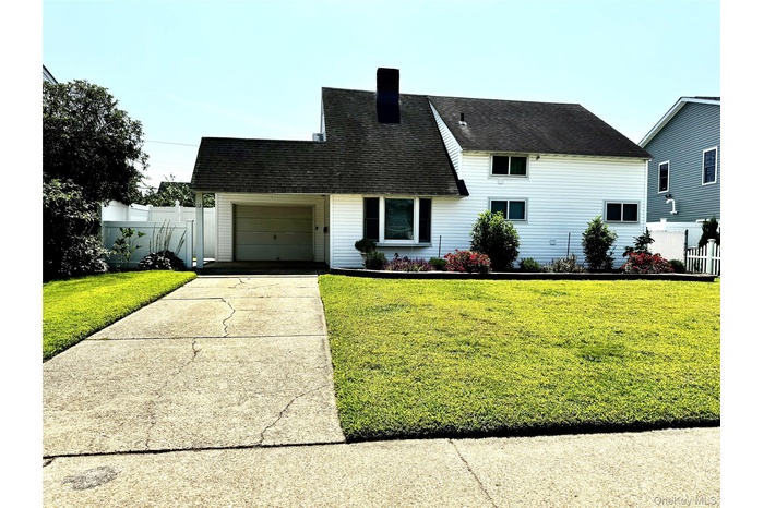 View of front of home featuring an attached garage, concrete driveway, roof with shingles, and a chimney