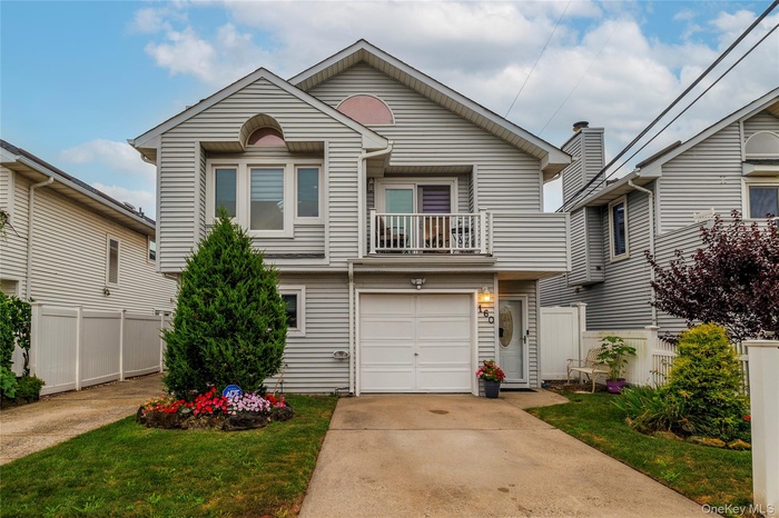 View of front of home with a balcony, driveway, and an attached garage