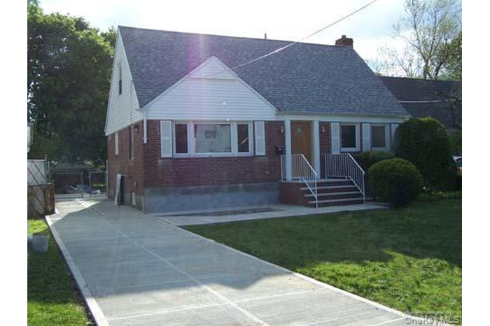 Bungalow featuring brick siding, a front yard, a chimney, and a porch