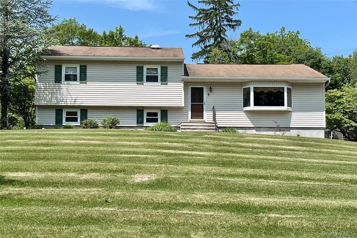 Split level home featuring a front yard and entry steps