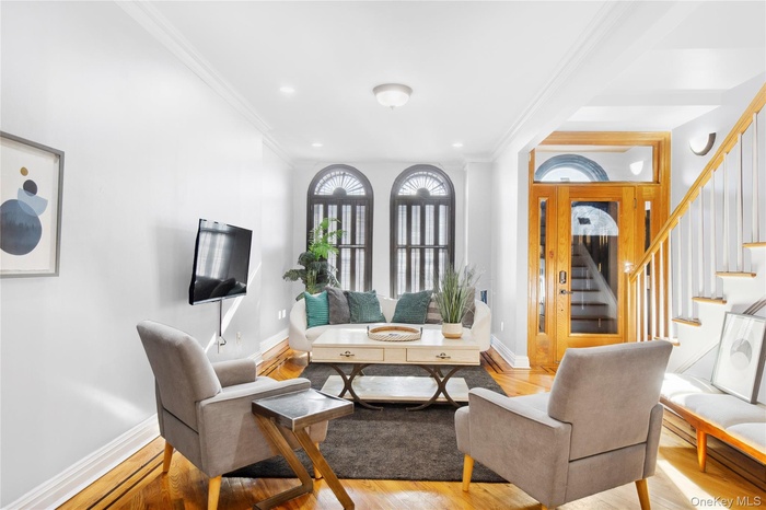 Living area featuring crown molding, light wood-style floors, and stairway