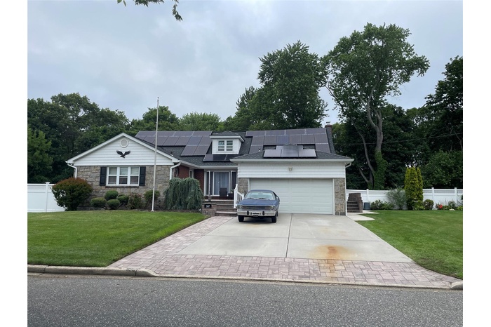Traditional-style house featuring stone siding, concrete driveway, a garage, and solar panels