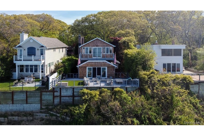Rear view of property with a fenced backyard, a chimney, a wooded view, a wooden deck, and a balcony