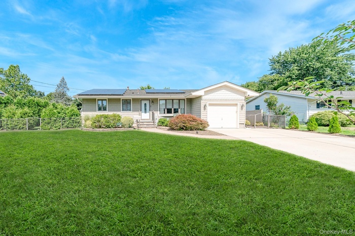 Ranch-style home featuring concrete driveway, an attached garage, solar panels and fenced