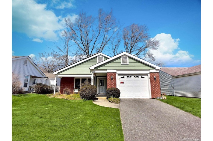 View of front of house with brick siding, a garage, and a front lawn